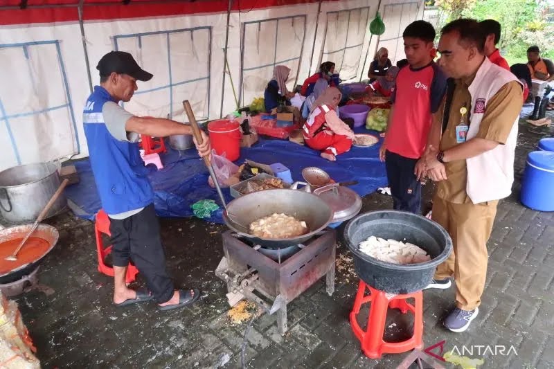 Kepala Dinas Sosial Lombok Barat Lalu Martajaya (kanan) meninjau aktivitas memasak makanan yang dilakukan petugas posko dapur umum di Kantor Camat Labuapi, Lombok Barat, Nusa Tenggara Barat, Selasa (11/2/2025). (ANTARA/Sugiharto Purnama)